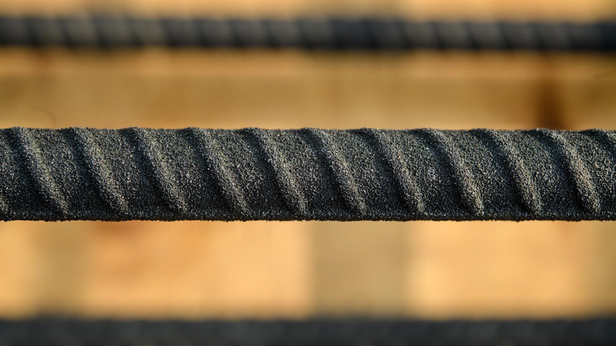 Close-up of the ASTM A1124 textured surface. The roughened outer layer is visibly and tactilely distinct from smooth coated bar.