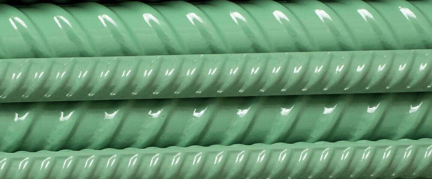 Close-up of epoxy coated rebar showing an intact green fusion-bonded epoxy coating conforming to the deformations of the bar